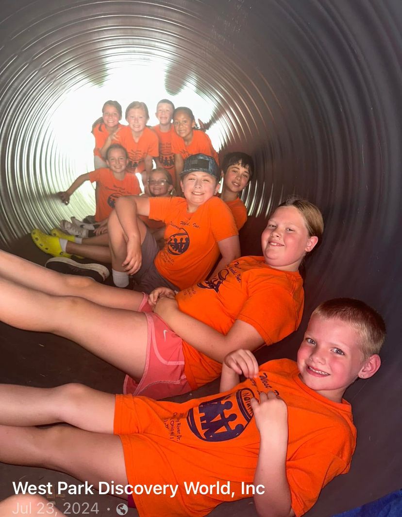 A group of children are laying in a tunnel at west park discovery world