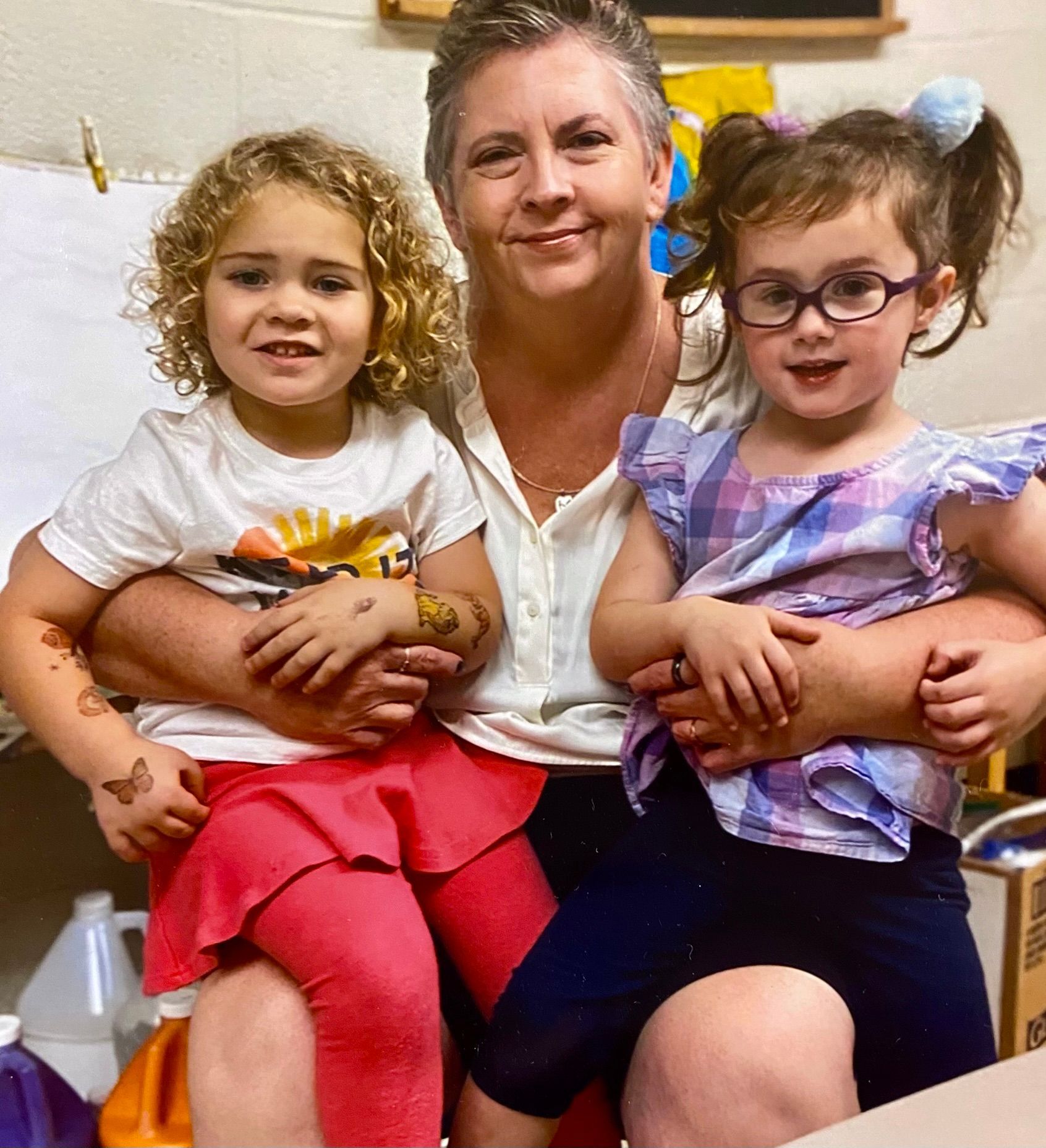 A woman and two little girls are posing for a picture