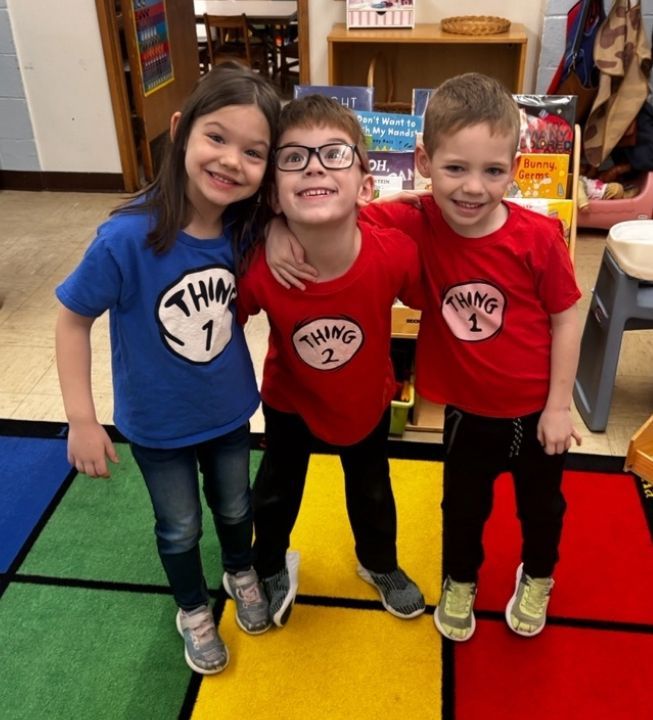 Three children wearing thing 1 and thing 2 shirts pose for a picture