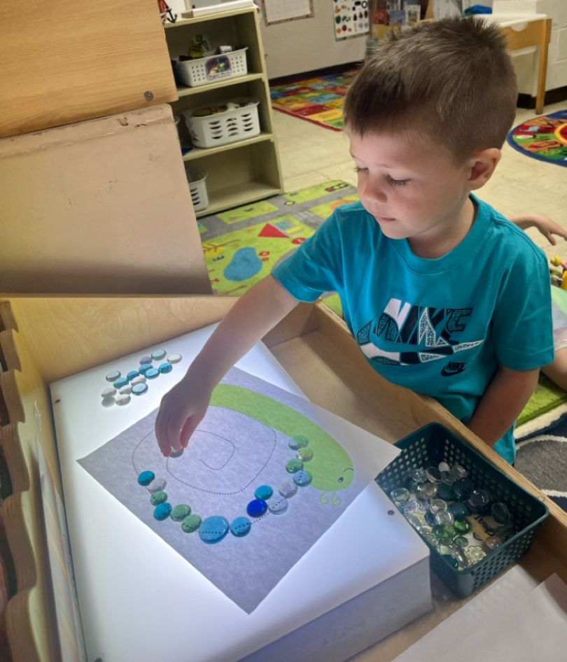 A young boy in a nike shirt is playing with a light box