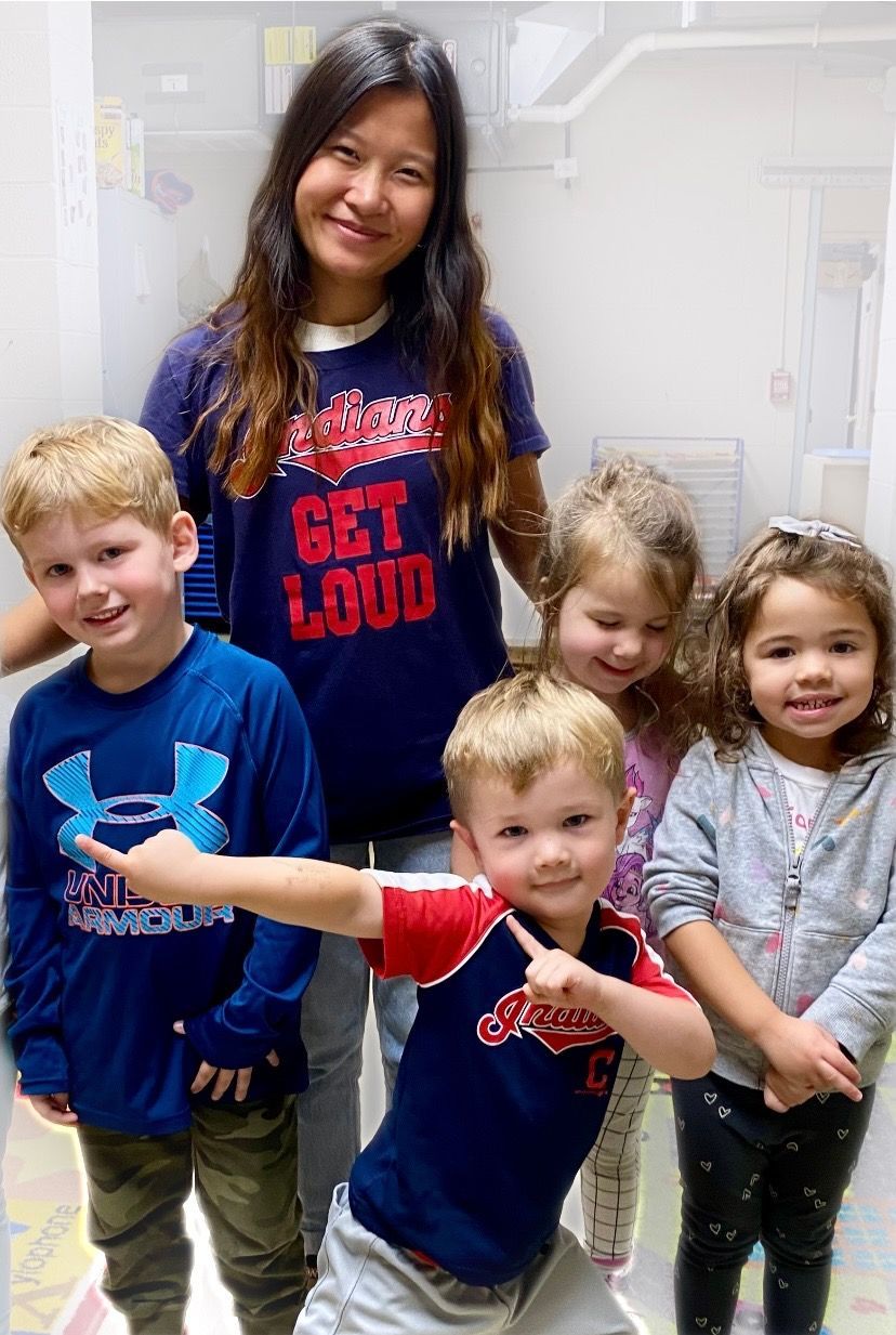 A woman is standing next to a group of children wearing shirts that say get loud.
