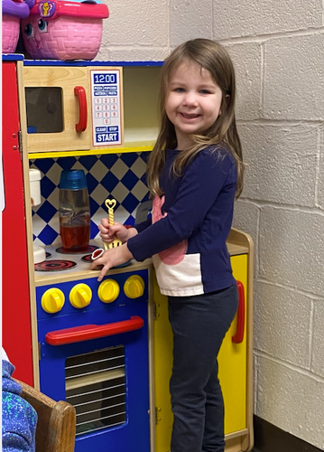 Little girl playing with a fake cooking station