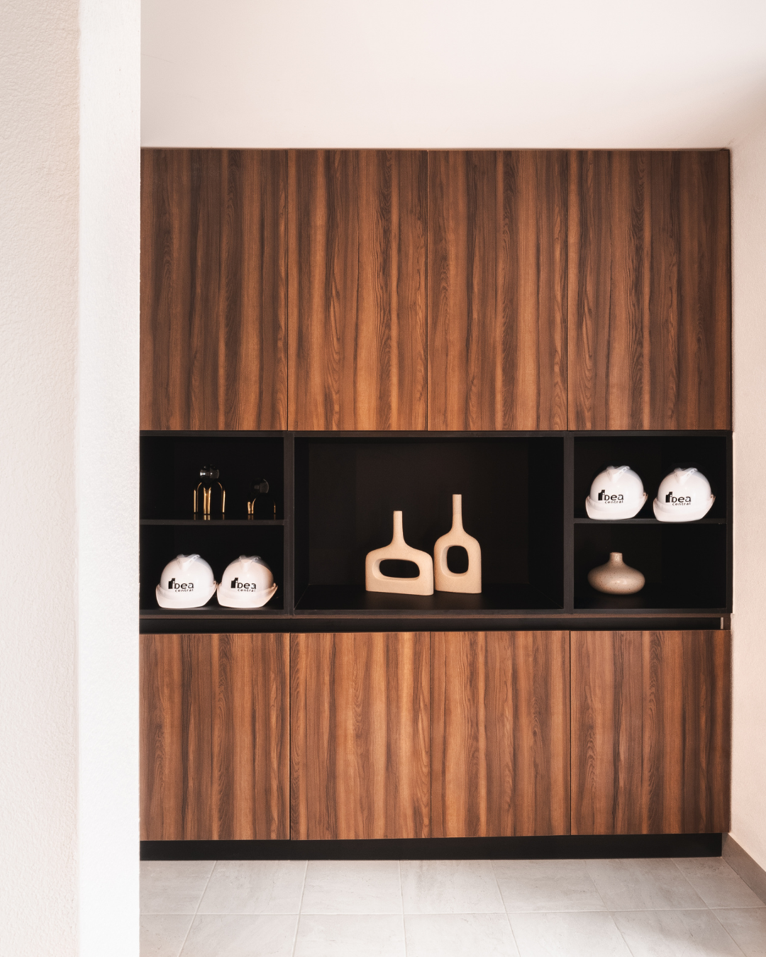 Una habitación con armarios de madera y un estante con dos jarrones encima.