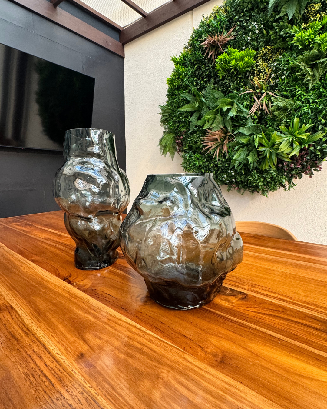 Dos jarrones están sobre una mesa de madera.