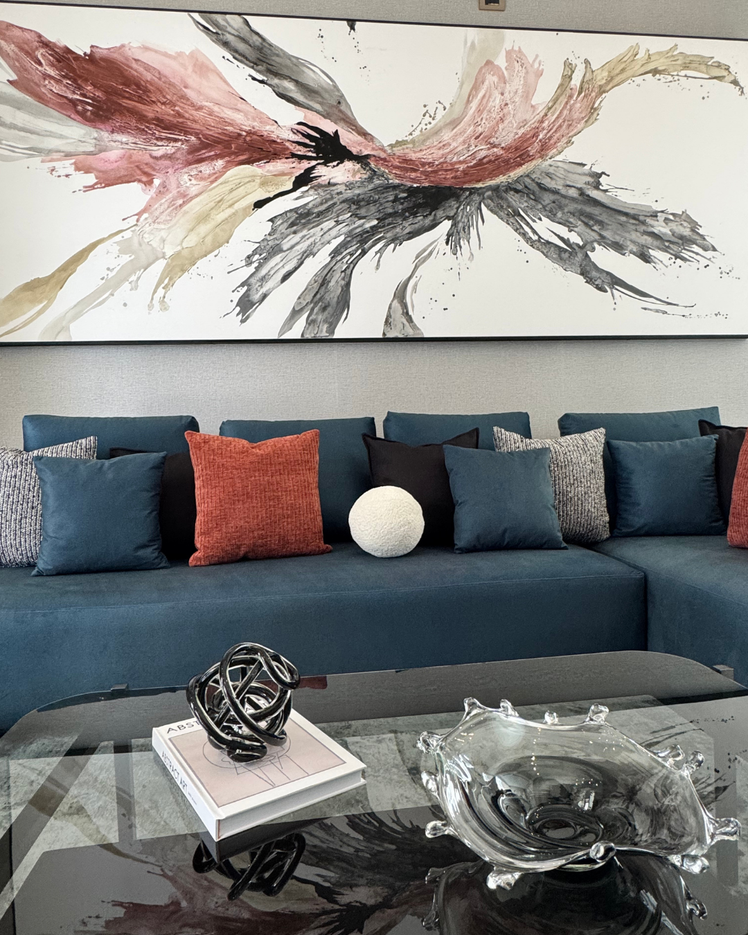 Una sala de estar con un sofá seccional azul y un cuadro grande en la pared encima de él.