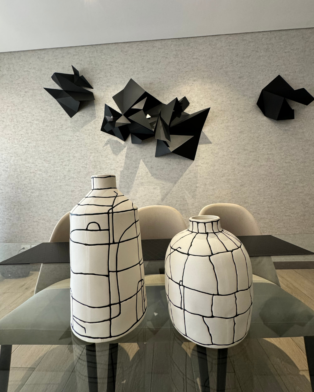 Dos jarrones están sobre una mesa de cristal en un comedor.