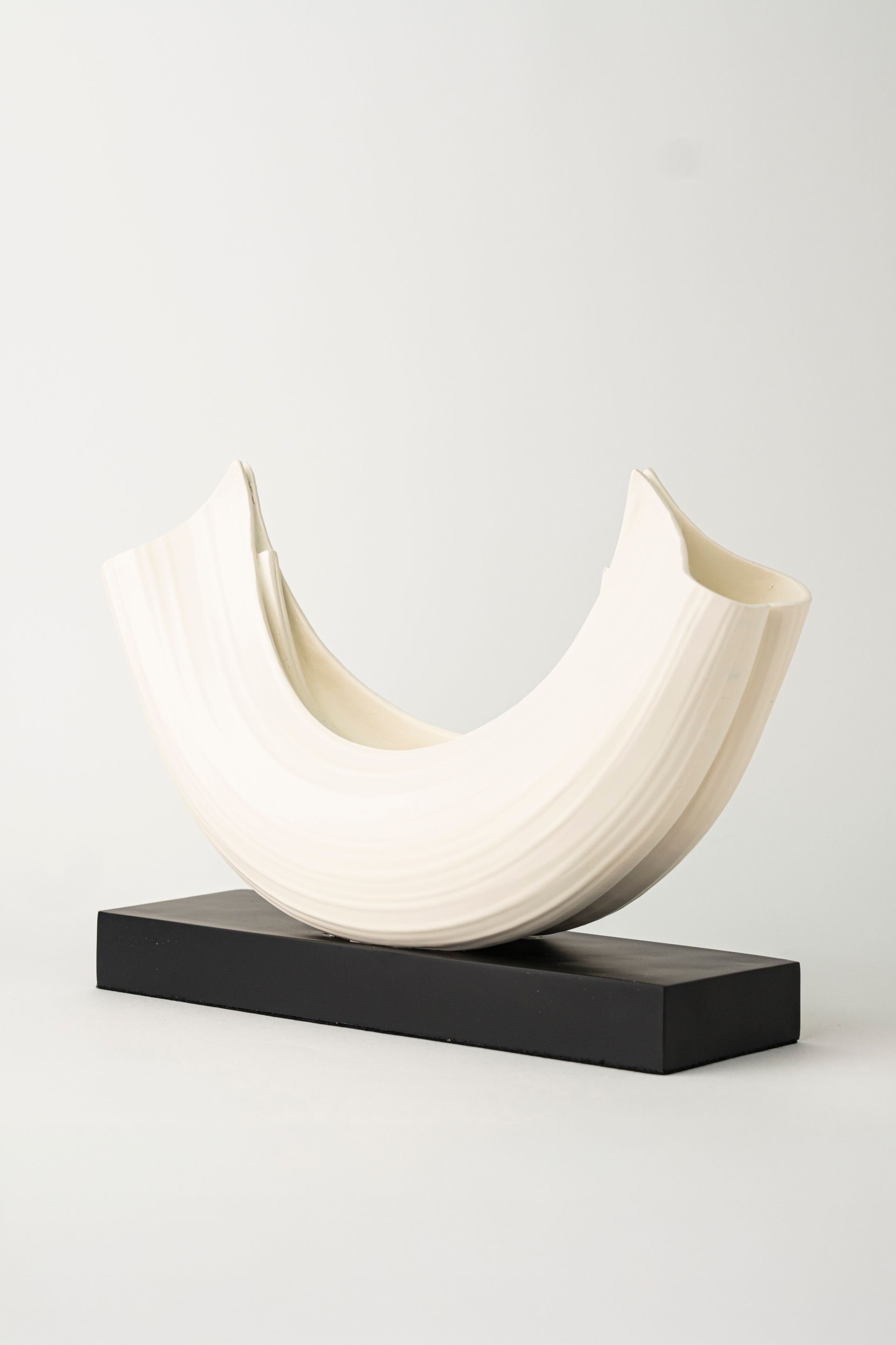 Una escultura blanca está sentada sobre una base negra sobre una mesa.
