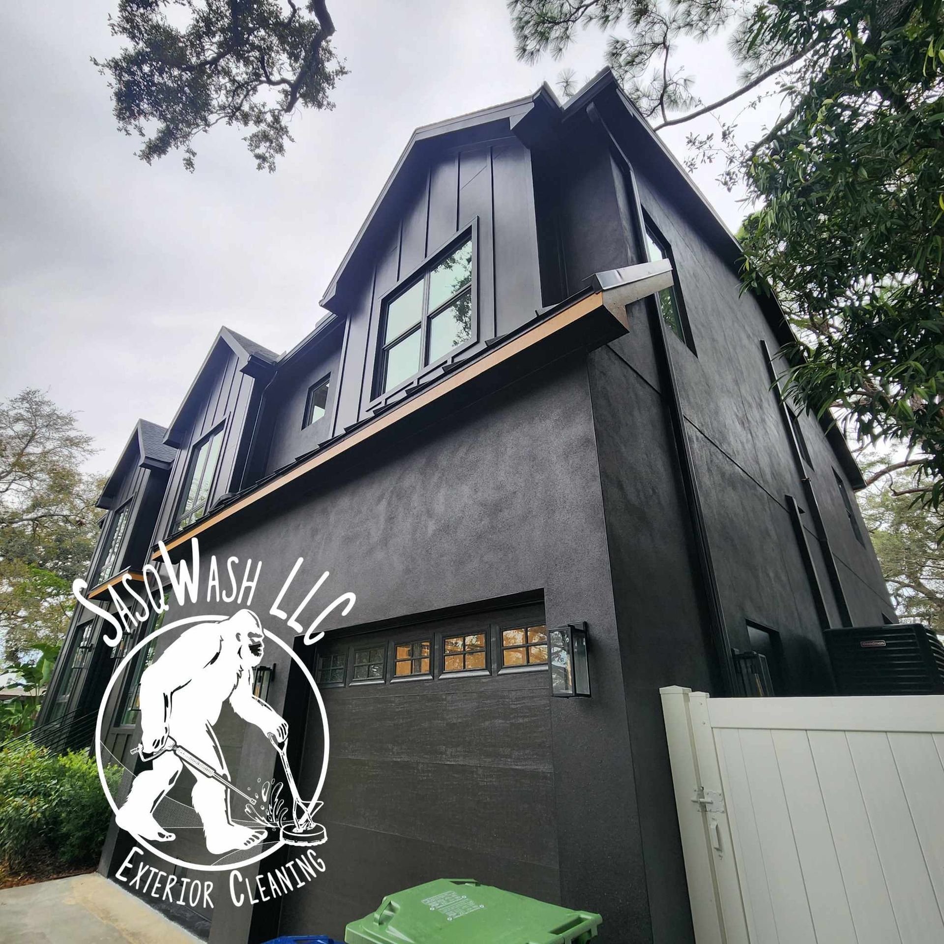 A large black house is being cleaned by sidewash llc