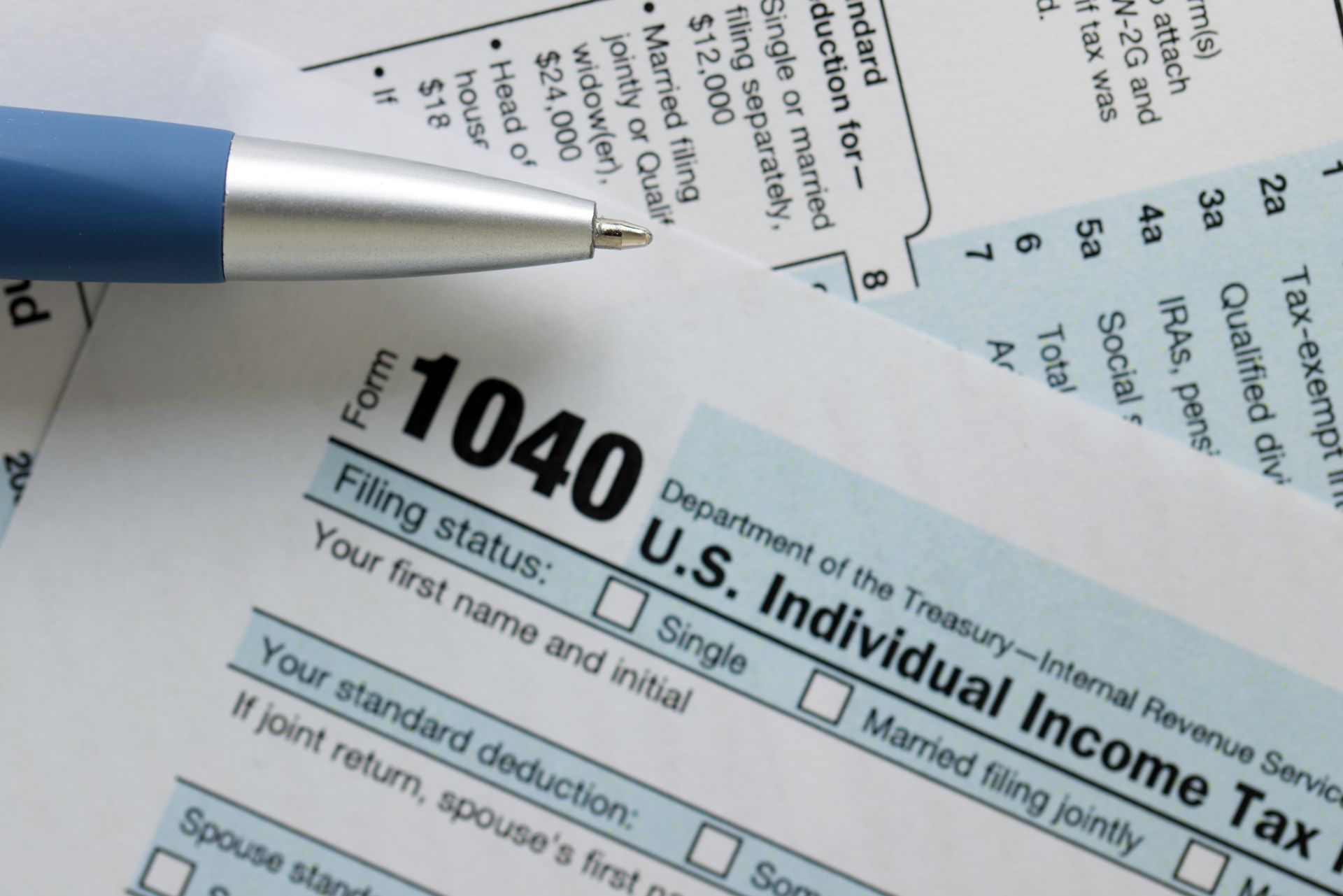 Close-up of a blue pen resting on top of a U.S. Individual Income Tax Form 1040.