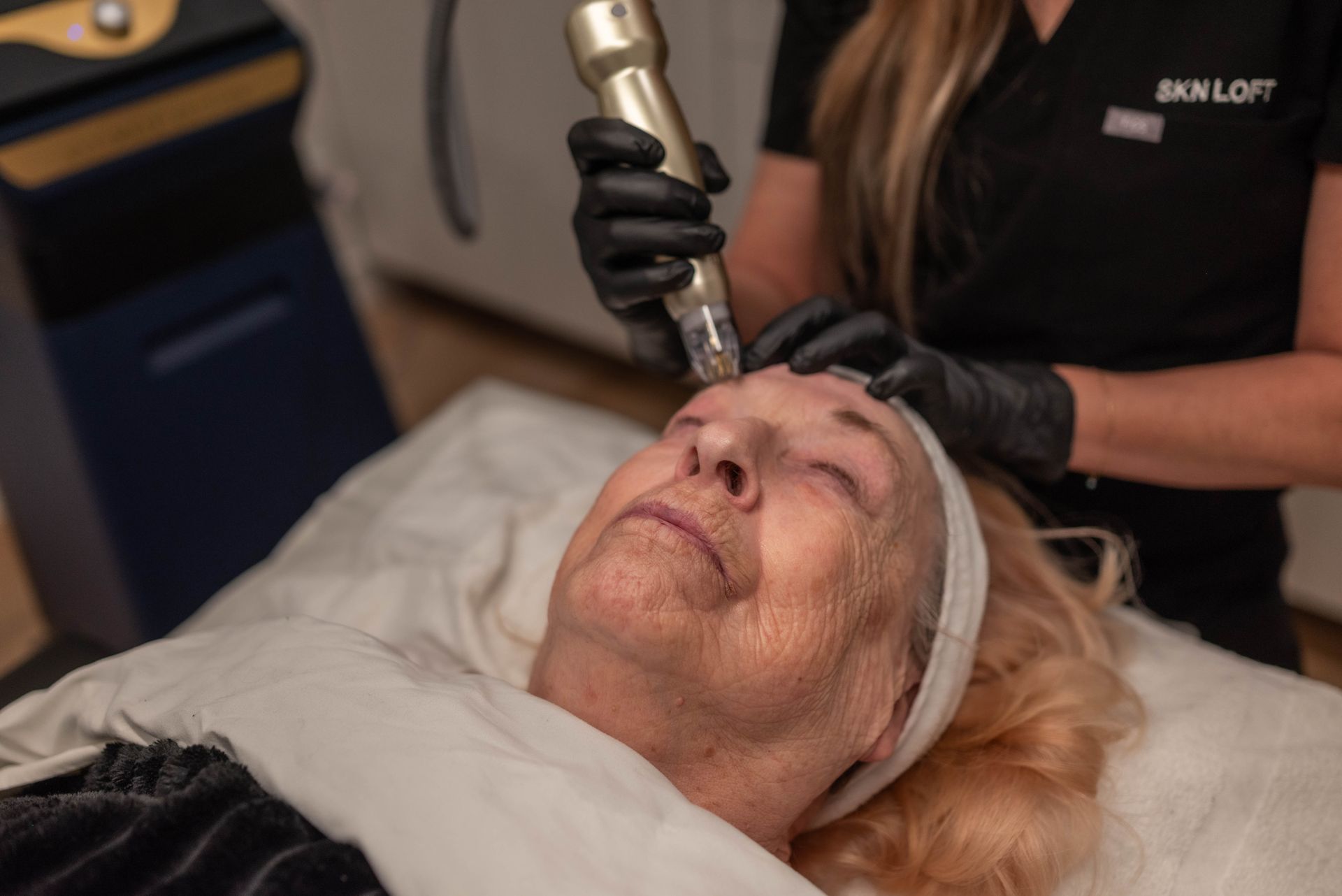A woman is laying on a bed getting a facial treatment.