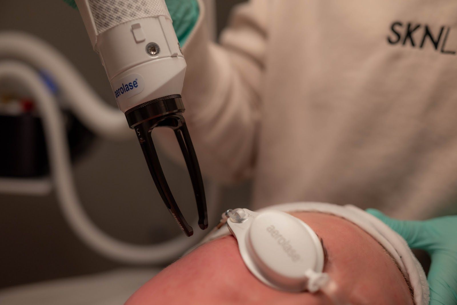 Person receiving facial laser treatment. Device held near the face, protective eyewear in place.
