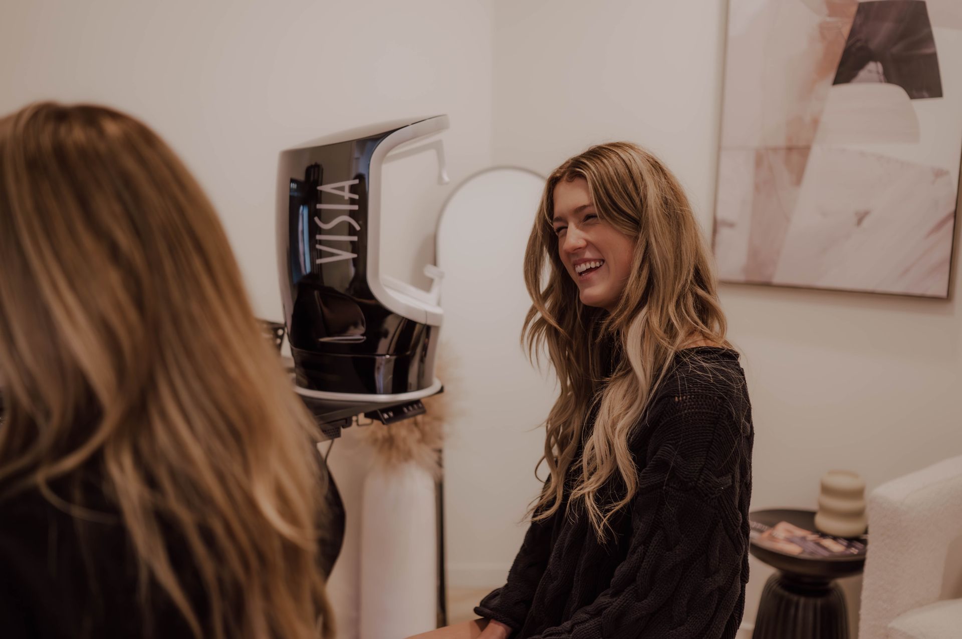 A woman is sitting in front of a mirror in a room.