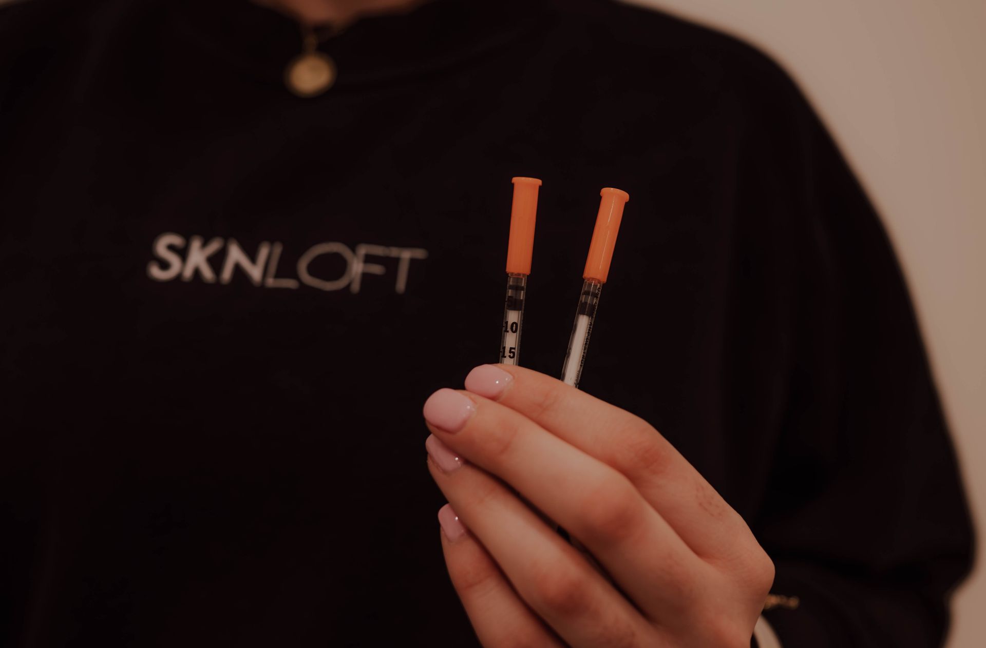 A woman is holding two syringes in her hands.