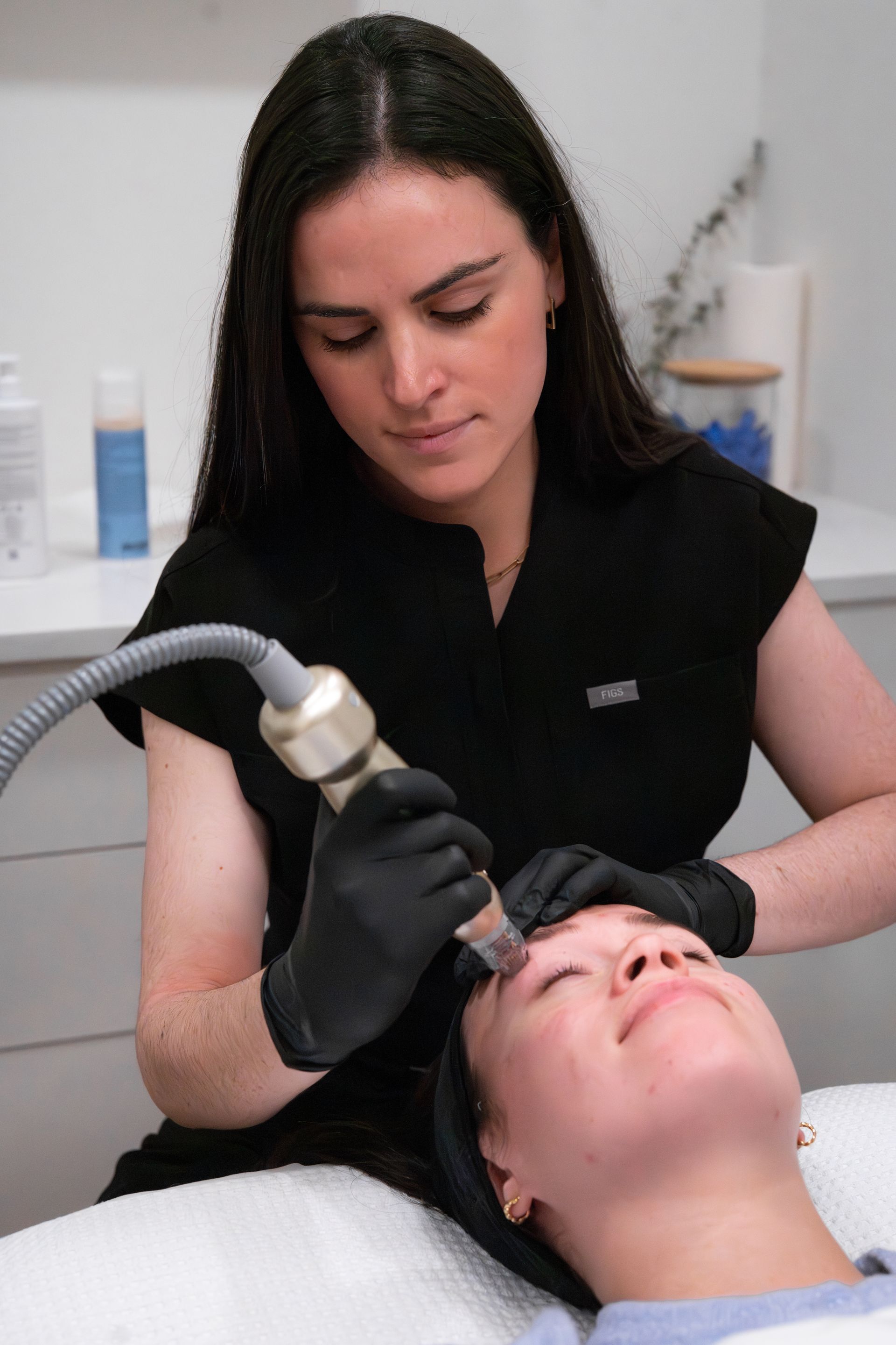 Woman performing a microneedling treatment on a client in a spa.