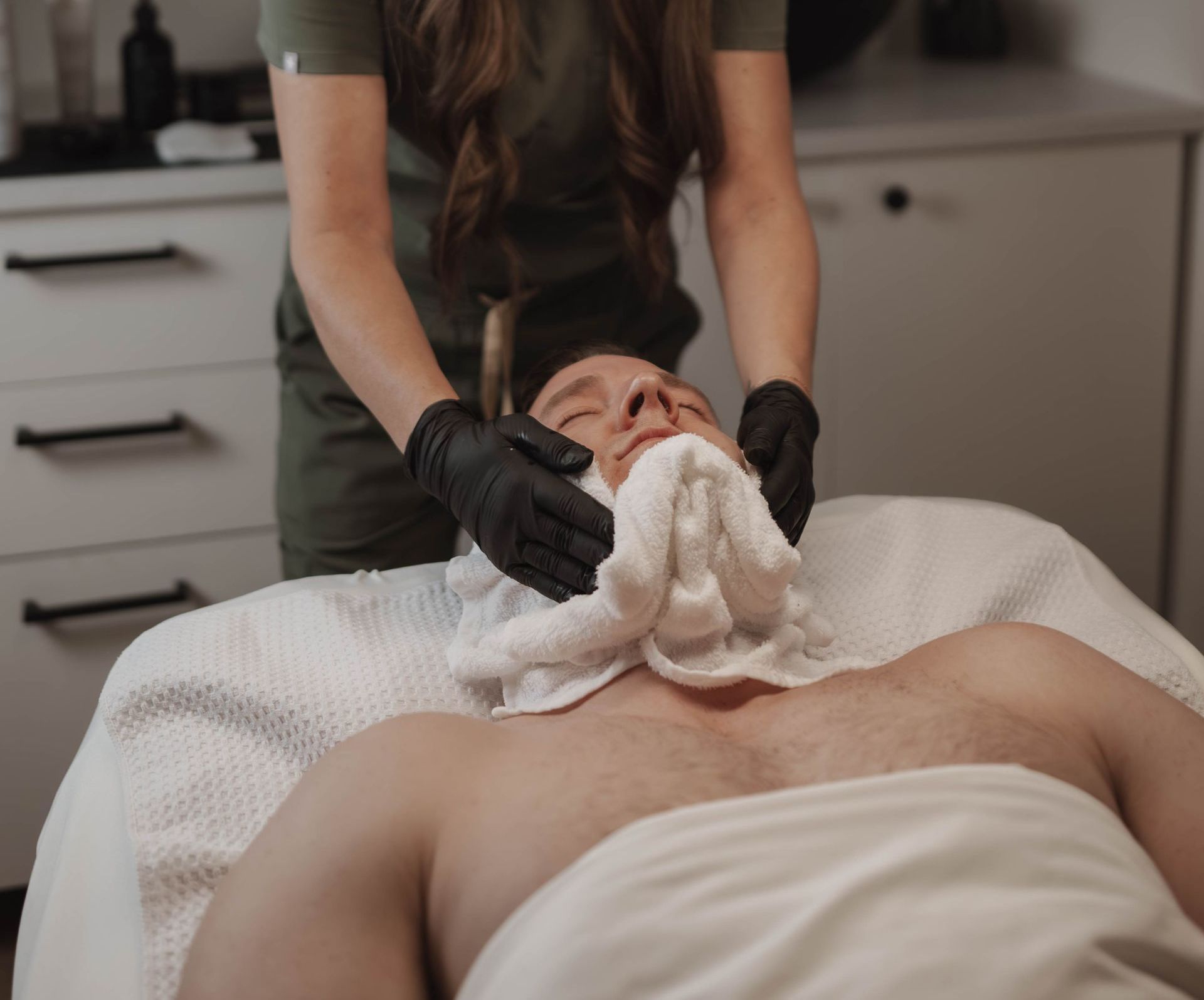A woman is getting a facial massage at a spa.