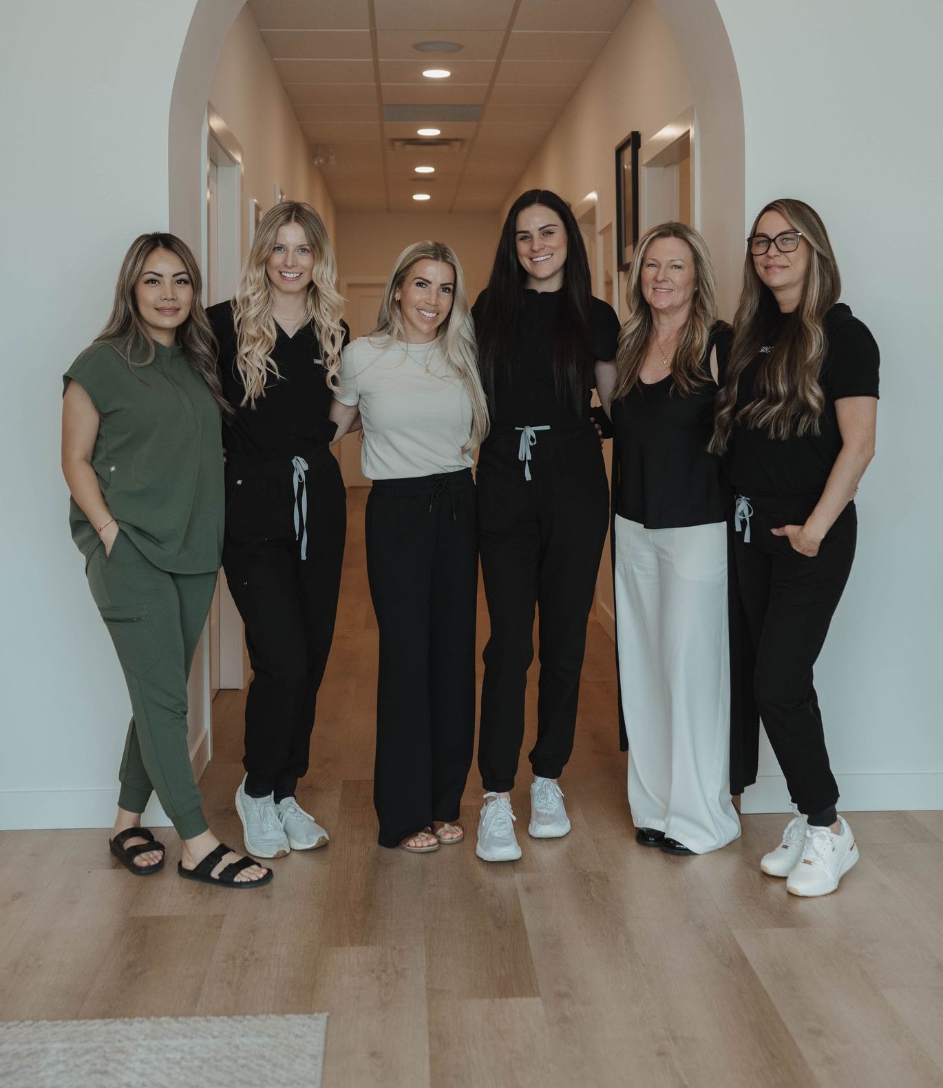 three women in black sweatshirts are posing for a picture in a hallway