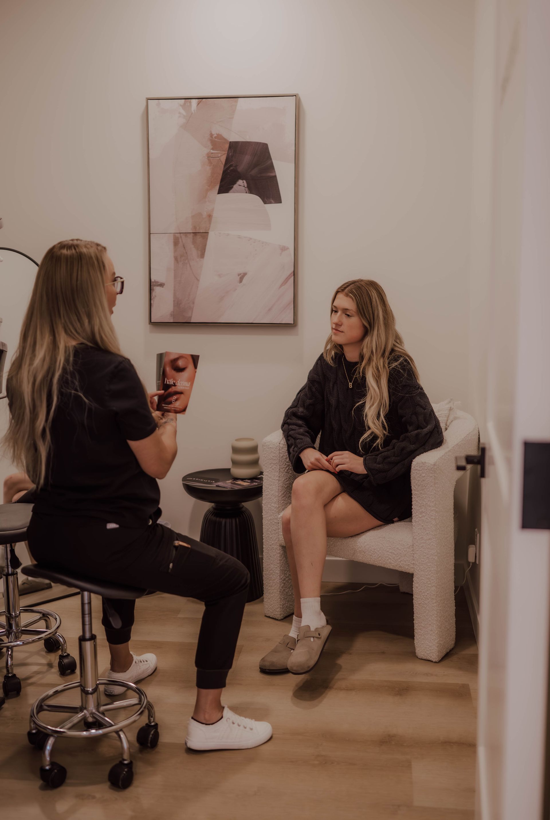 Woman in a medical setting consults with a patient. The woman holds a face diagram while they talk.