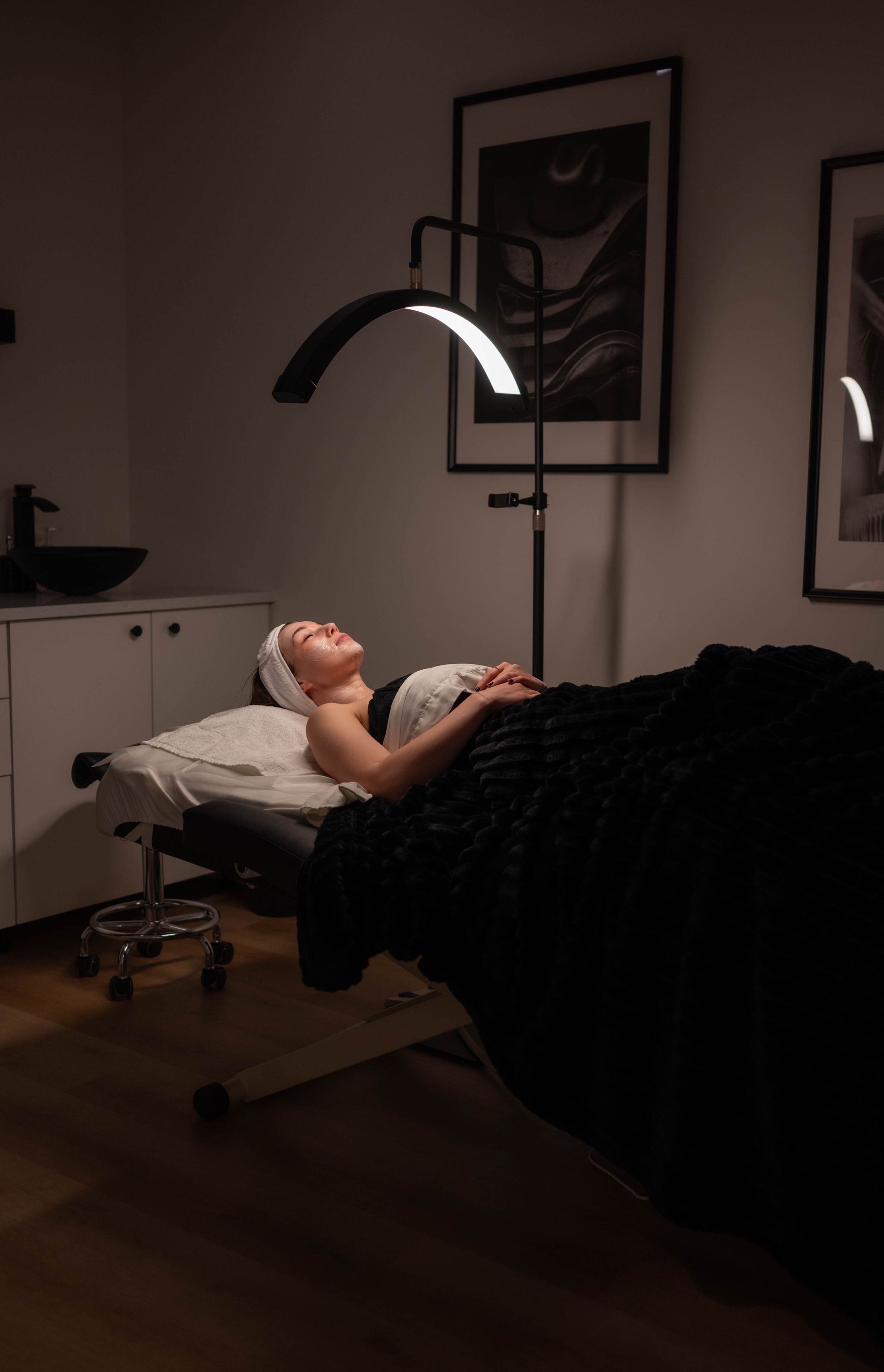 A woman is laying on a massage table in a dark room.