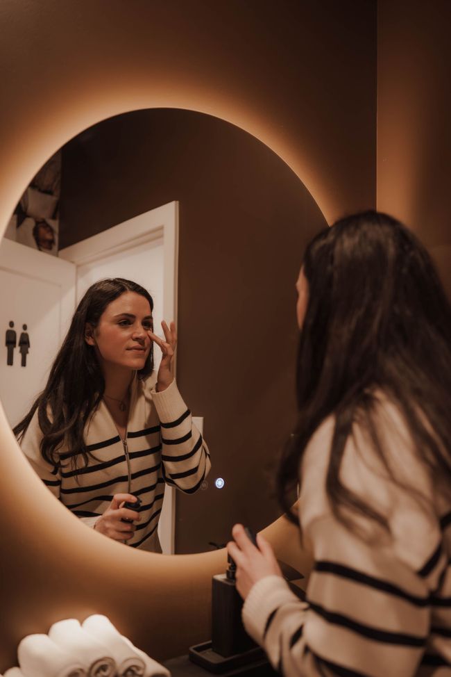 a woman is looking at herself in the mirror .