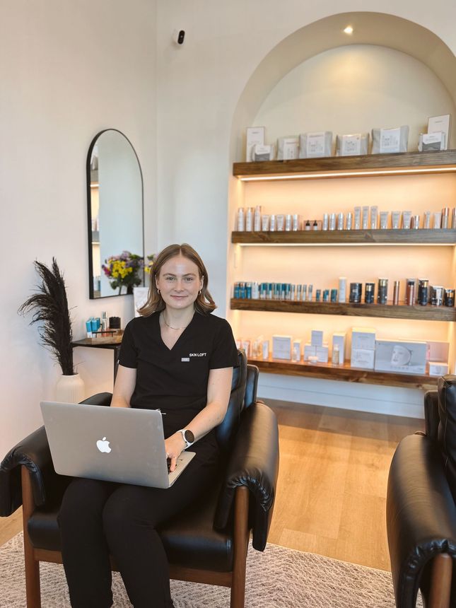 A woman is sitting in a chair with a laptop on her lap