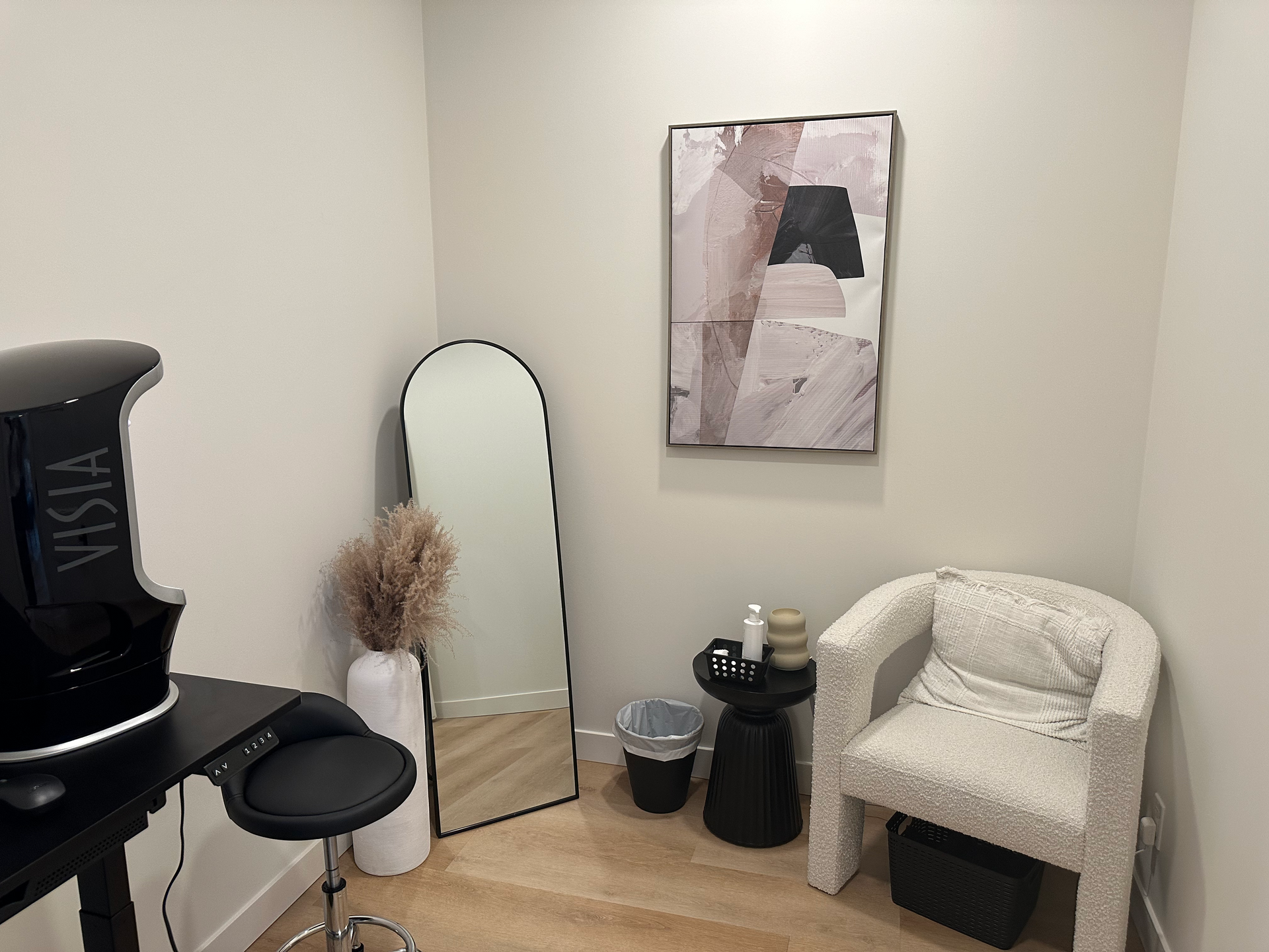 A room with a chair , table , mirror and a painting on the wall.