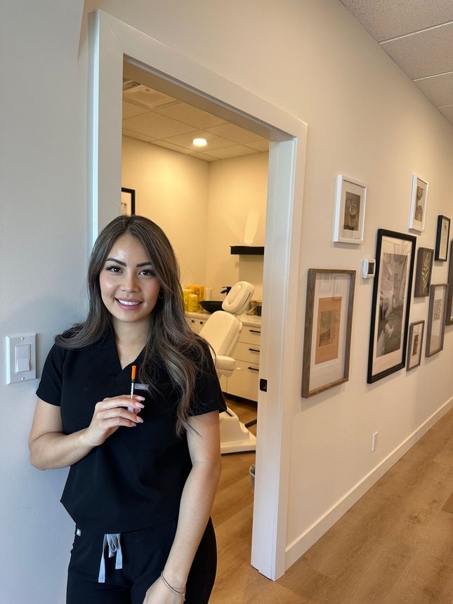 A woman is standing in a hallway holding a syringe.