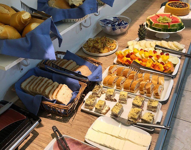 O buffet de café da manhã do hotel inclui cestas de pães, frutas fatiadas, bolos, doces e uma variedade de carnes e queijos.