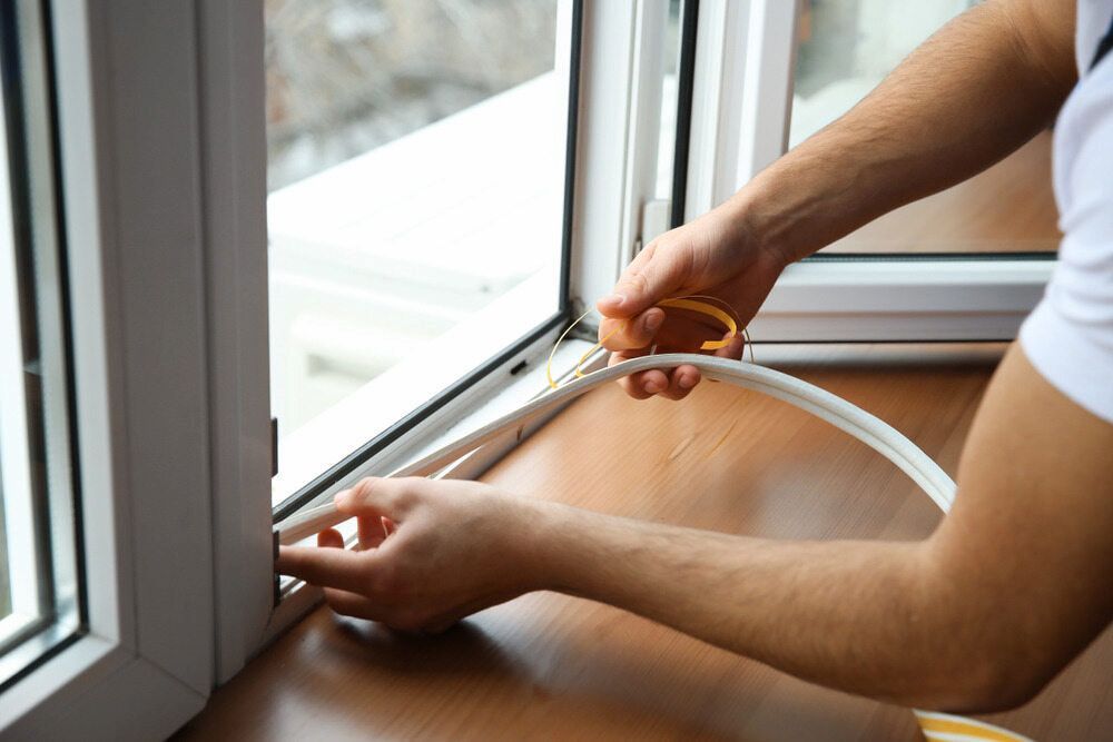 A Man is Installing a Window Seal on a Window Sill — Bulli Glass in Bulli, NSW
