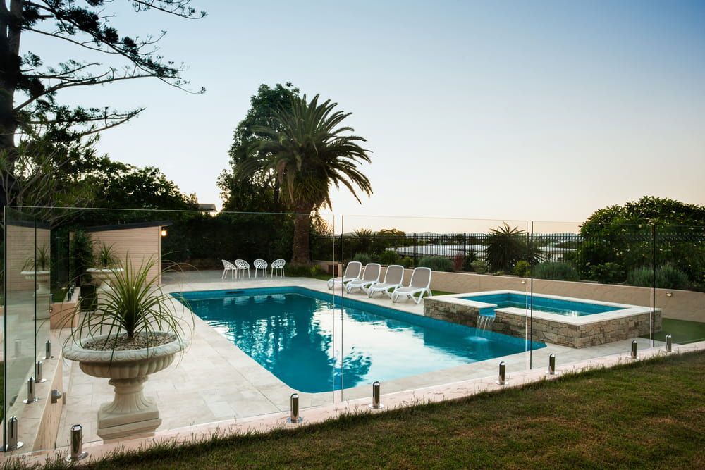 A Large Swimming Pool With a Glass Fence Around It — Bulli Glass in Bulli, NSW