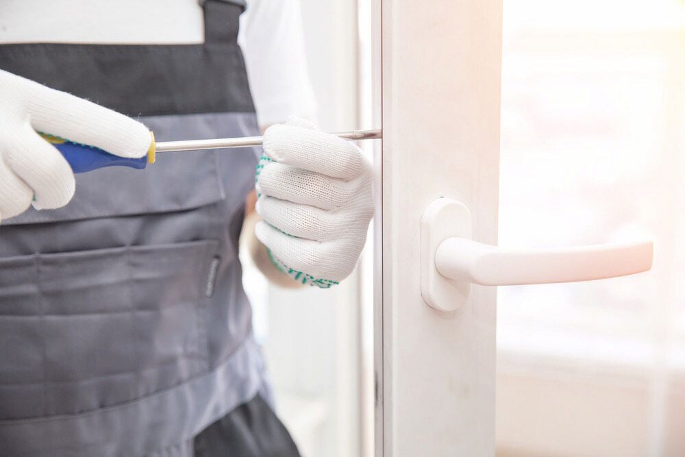 A Man is Fixing a Door with a Screwdriver — Bulli Glass in Bulli, NSW
