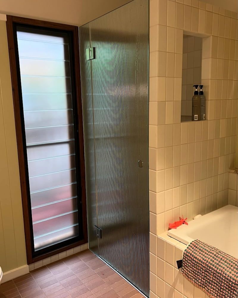 A Bathroom with a Glass Shower Door and a Bathtub — Bulli Glass in Wollongong, NSW