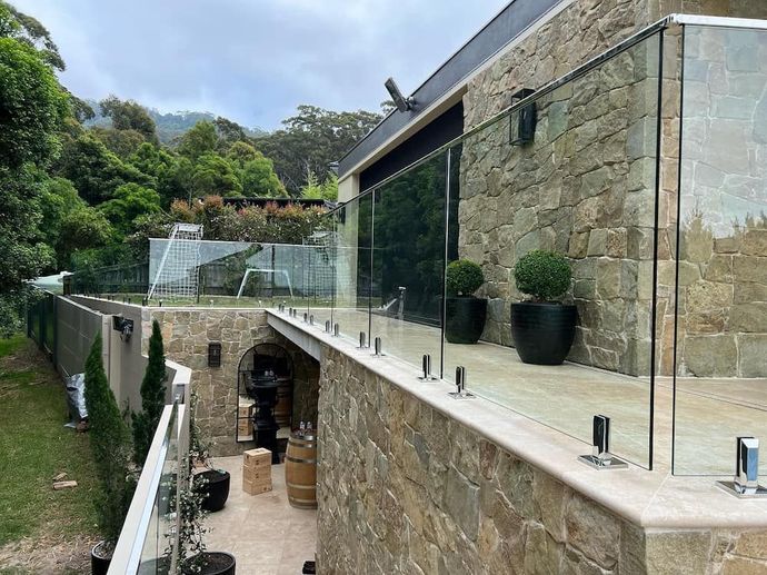A Large Stone Building with a Glass Railing on the Side of It ā Bulli Glass in Bulli, NSW