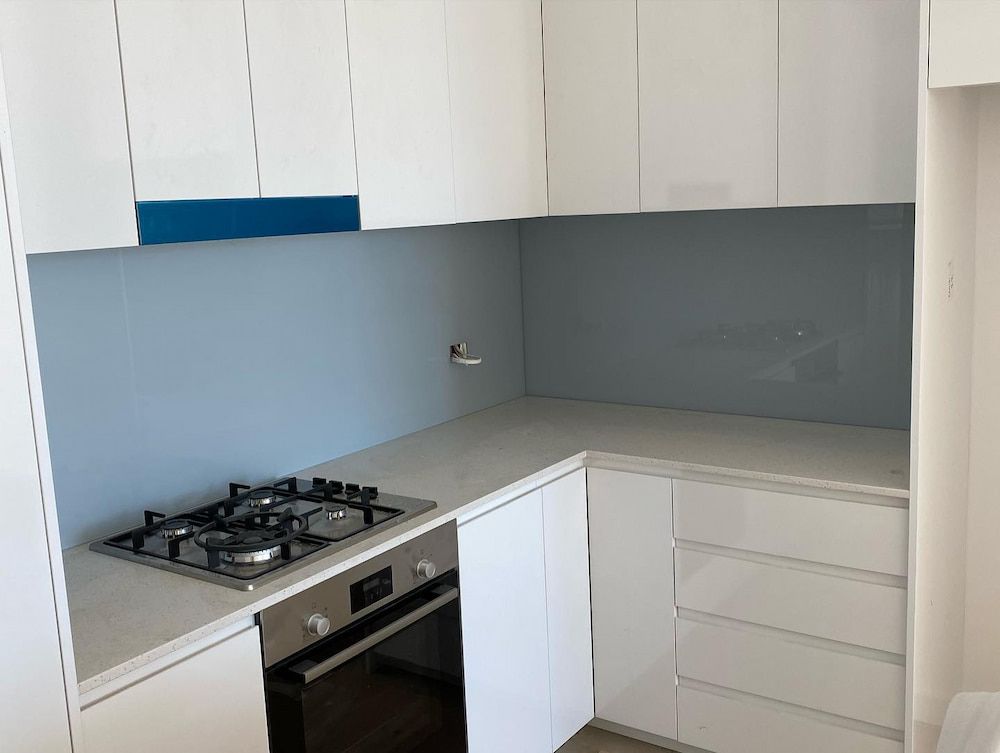 A Kitchen with White Cabinets and a Stove Top Oven — Bulli Glass in Bulli, NSW