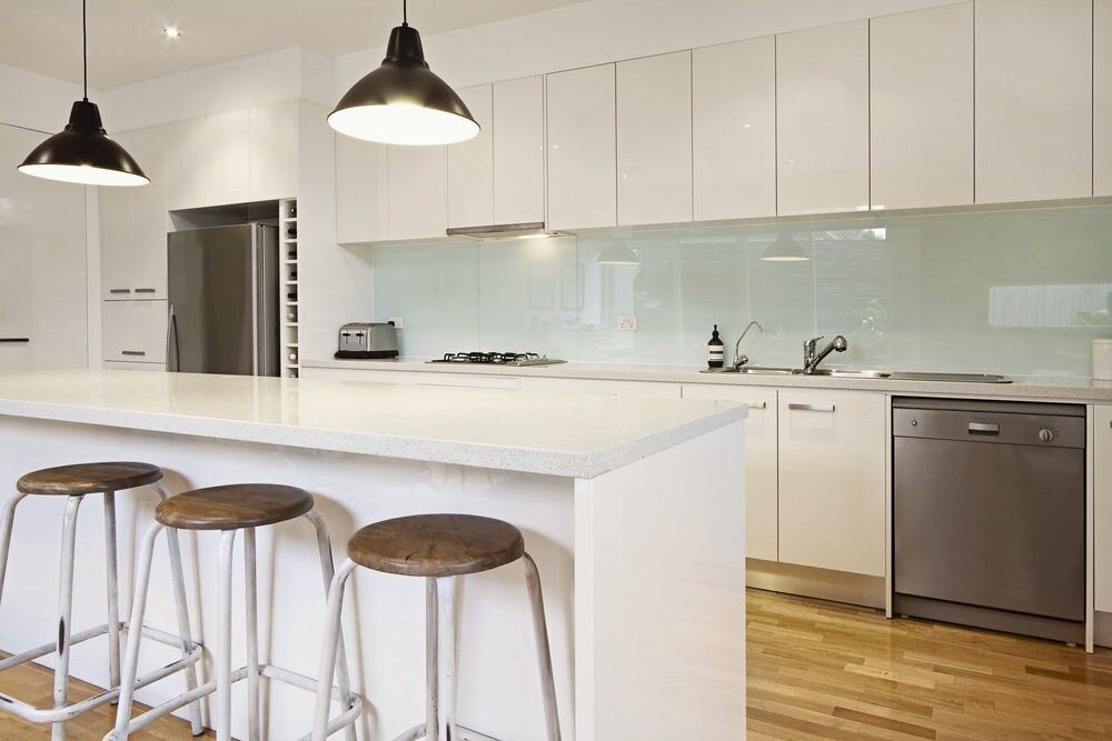 A Kitchen with White Cabinets, Stools, a Dishwasher and a Refrigerator — Bulli Glass in Bulli, NSW