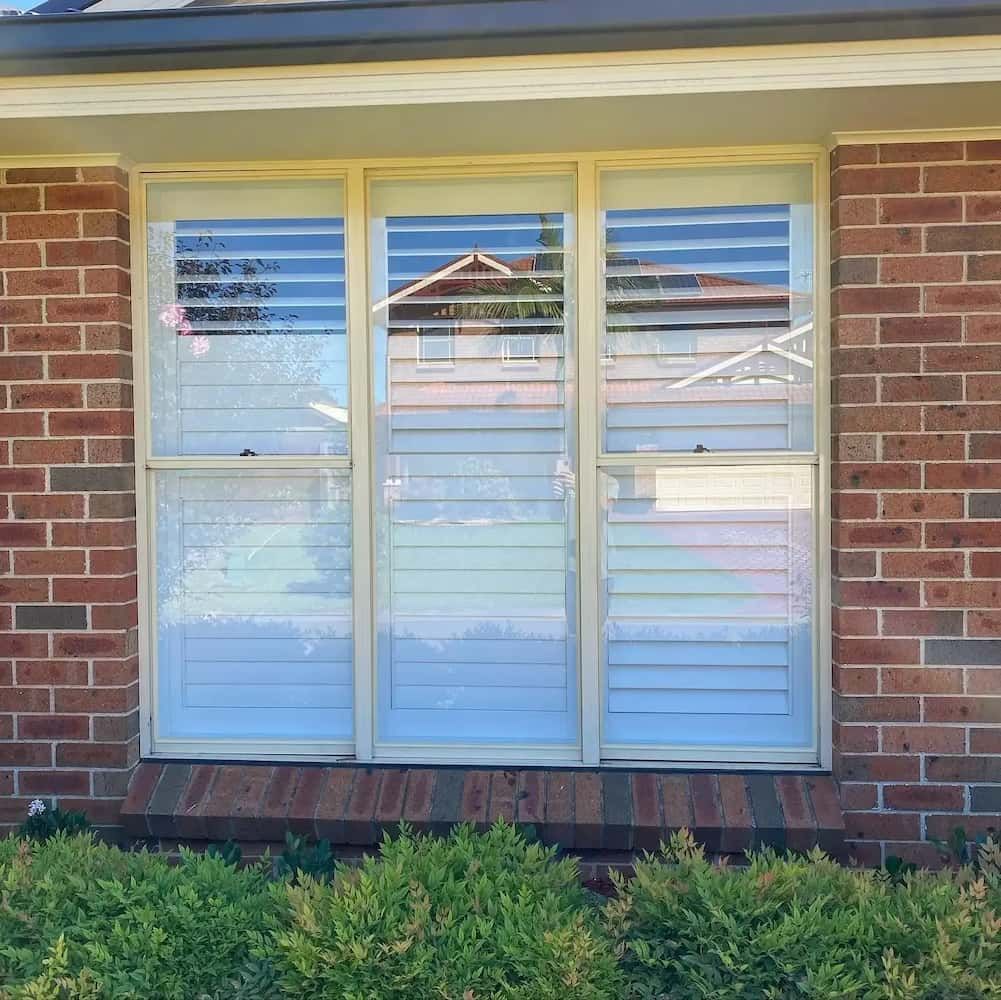 A Brick Building with a Window with Blinds on It — Bulli Glass in Bulli, NSW