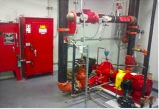 Red fire pump system with piping, valves, and control panels in a room.