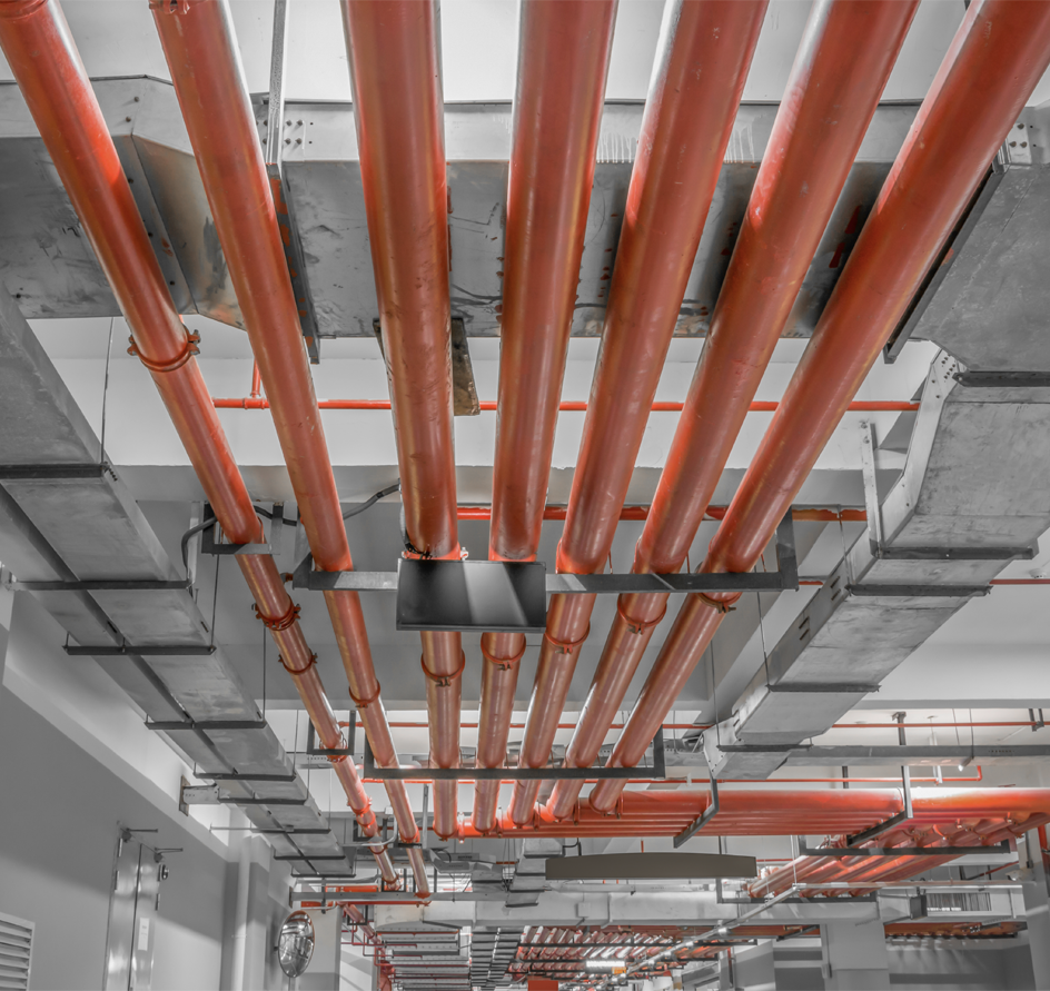 Red pipes run across a concrete ceiling, likely for fire suppression or plumbing.