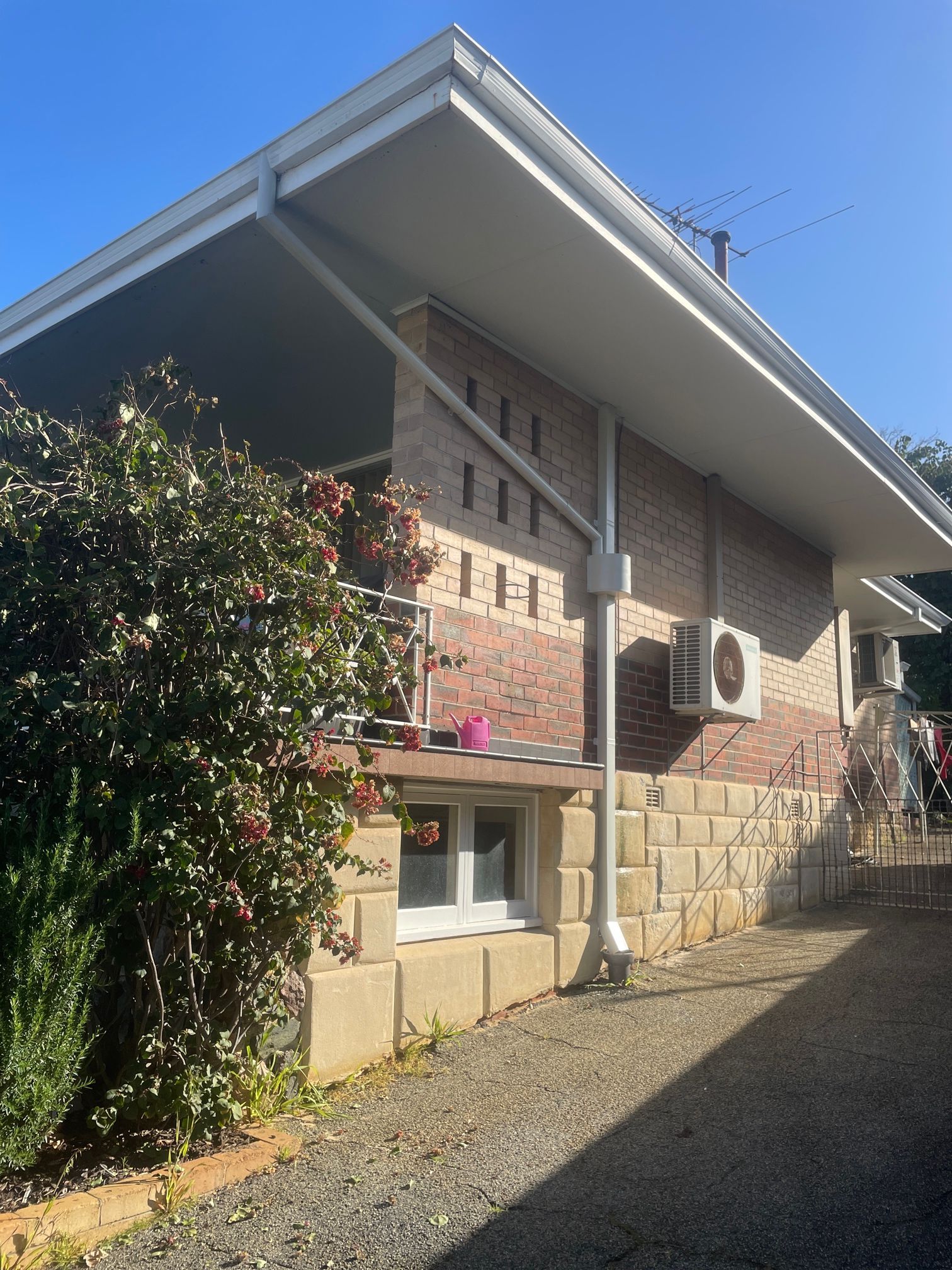 Down Pipe Installation Image a brick house with a white roof and a few trees in front of it .