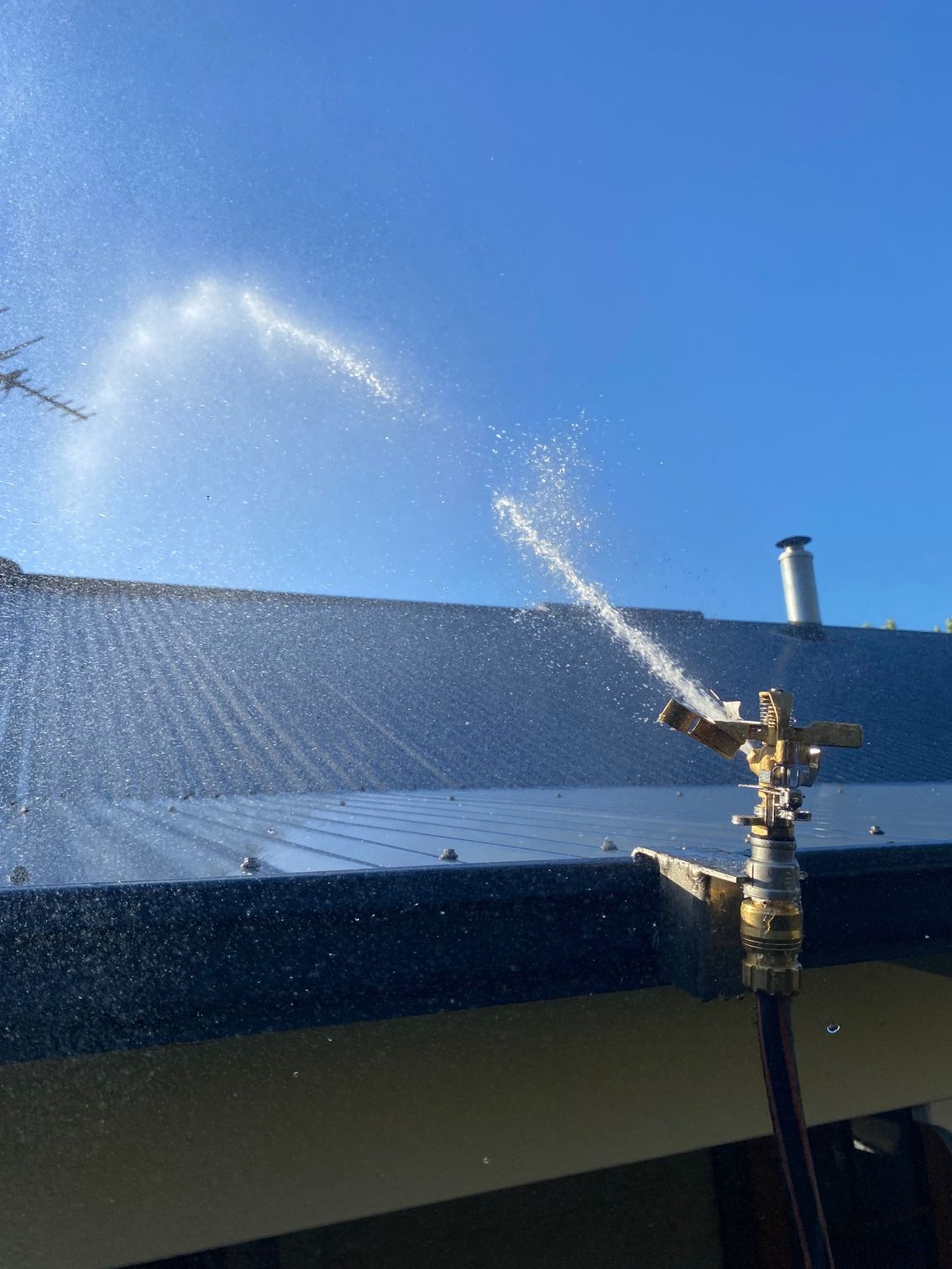 Rainmaker Bushfire Sprinkler Image A sprinkler is spraying water on the roof of a building.
