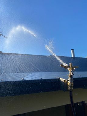 A sprinkler is spraying water on the roof of a building.