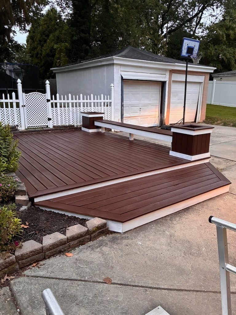 Brown composite deck with white trim and a garage in the background.