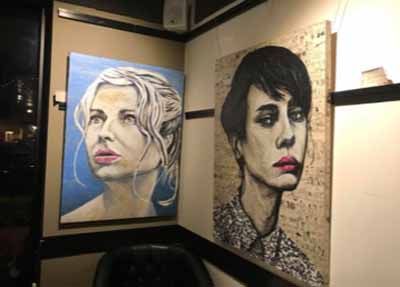 Two paintings of women are hanging on a wall in a room.