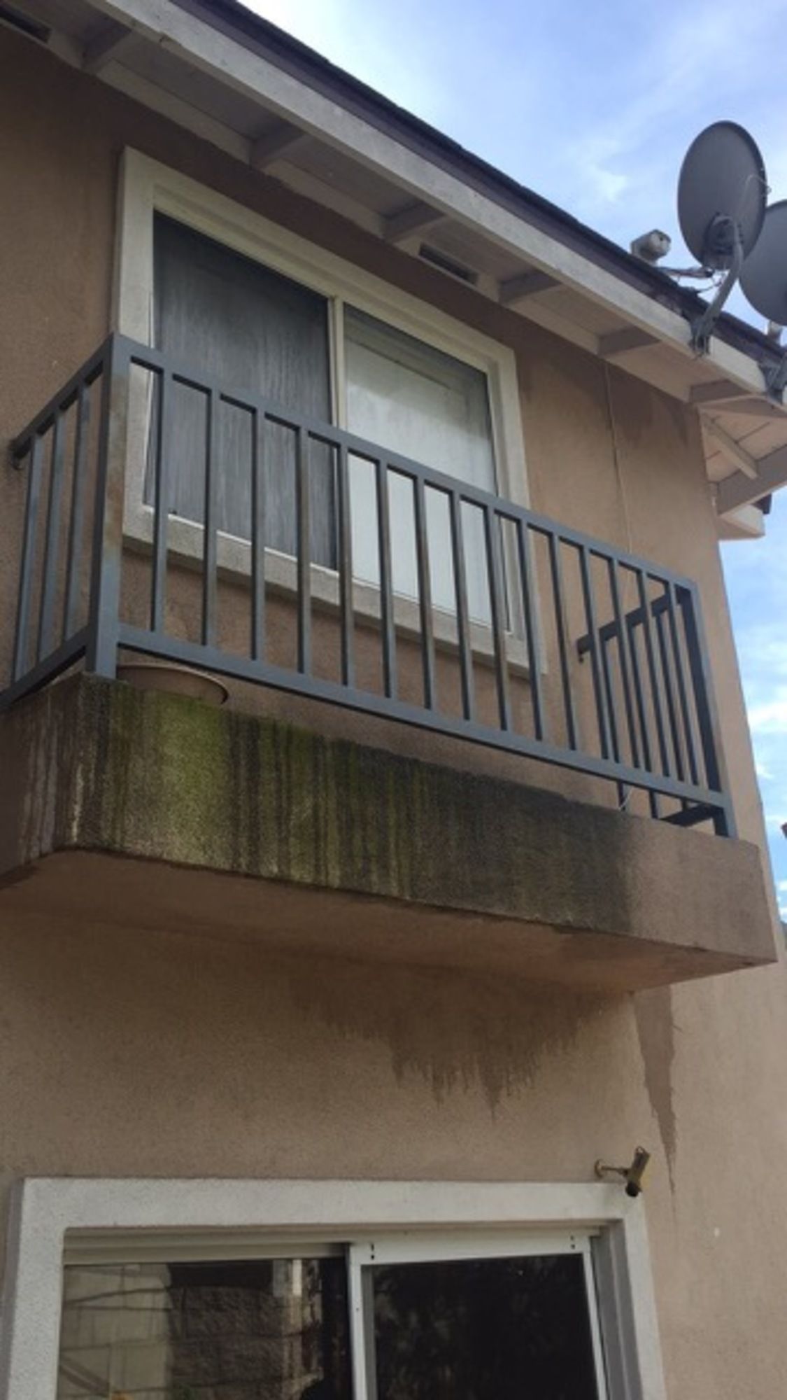 A balcony on the side of a building with a satellite dish on the roof.