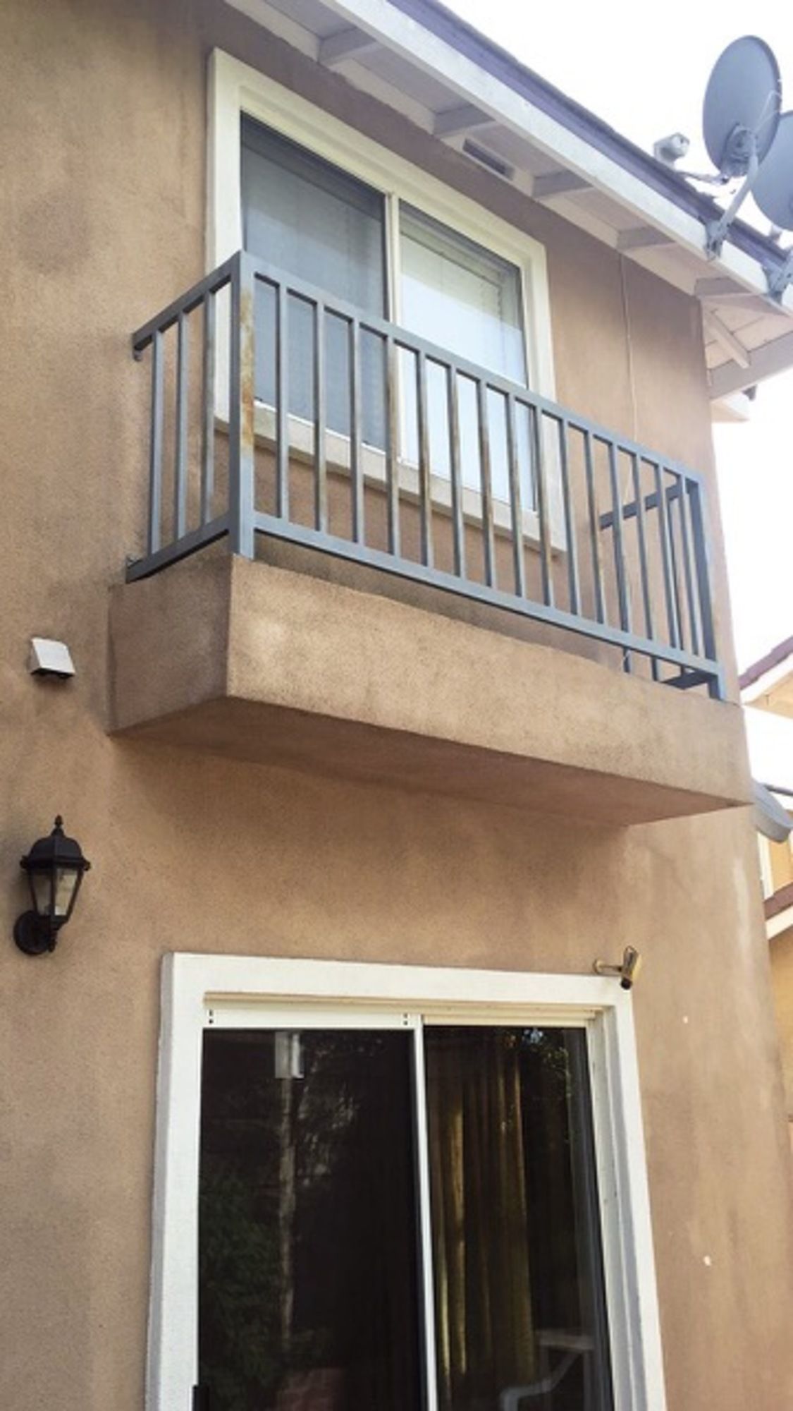 A balcony on the side of a house with a sliding glass door