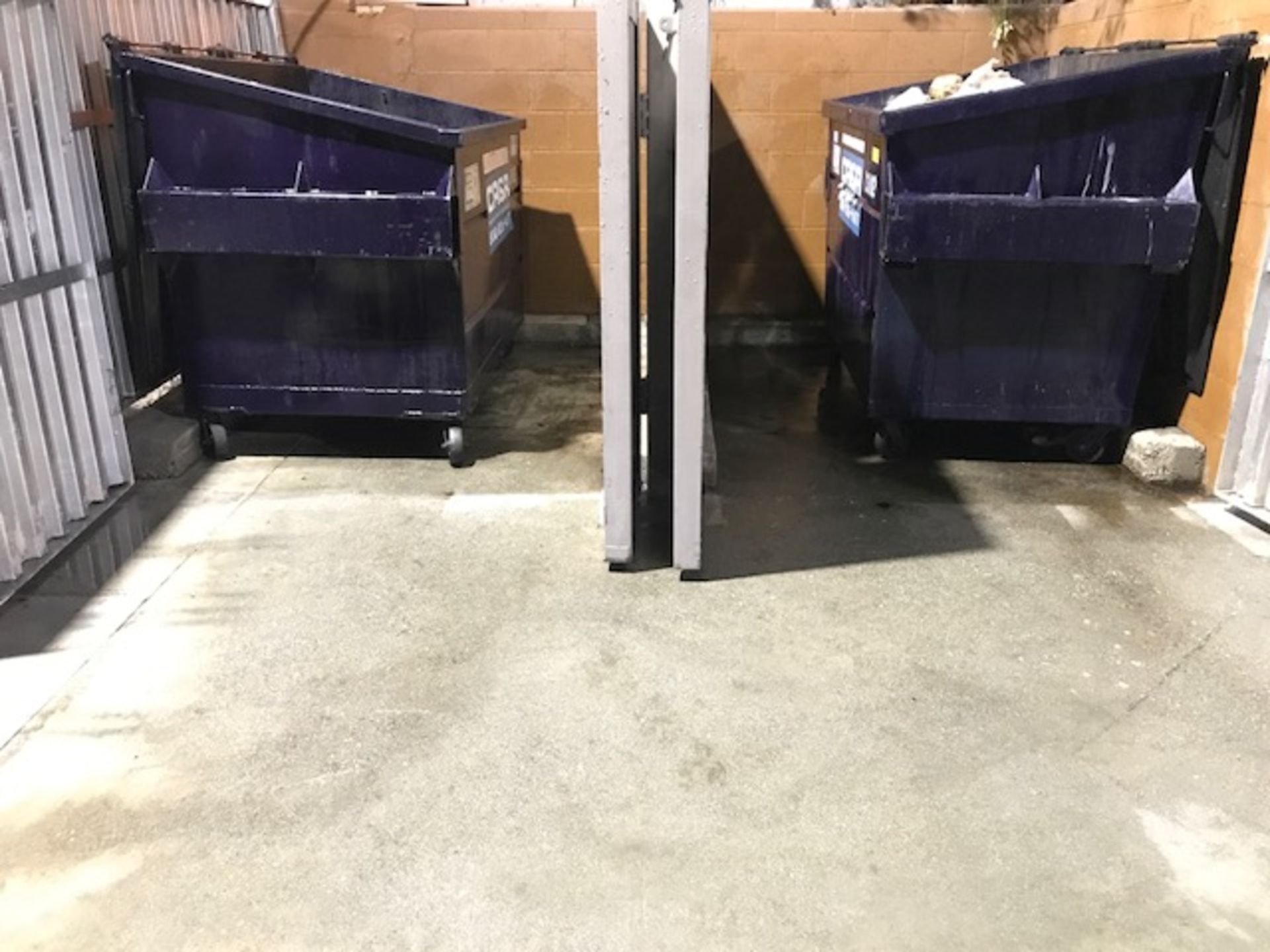 Two blue dumpsters are sitting next to each other in a room.