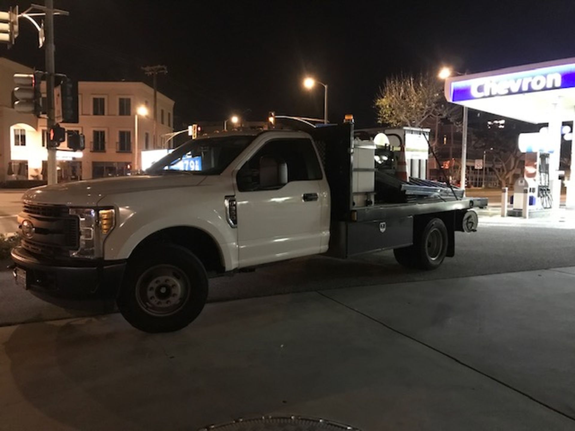 A white truck is parked in front of a gas station at night.