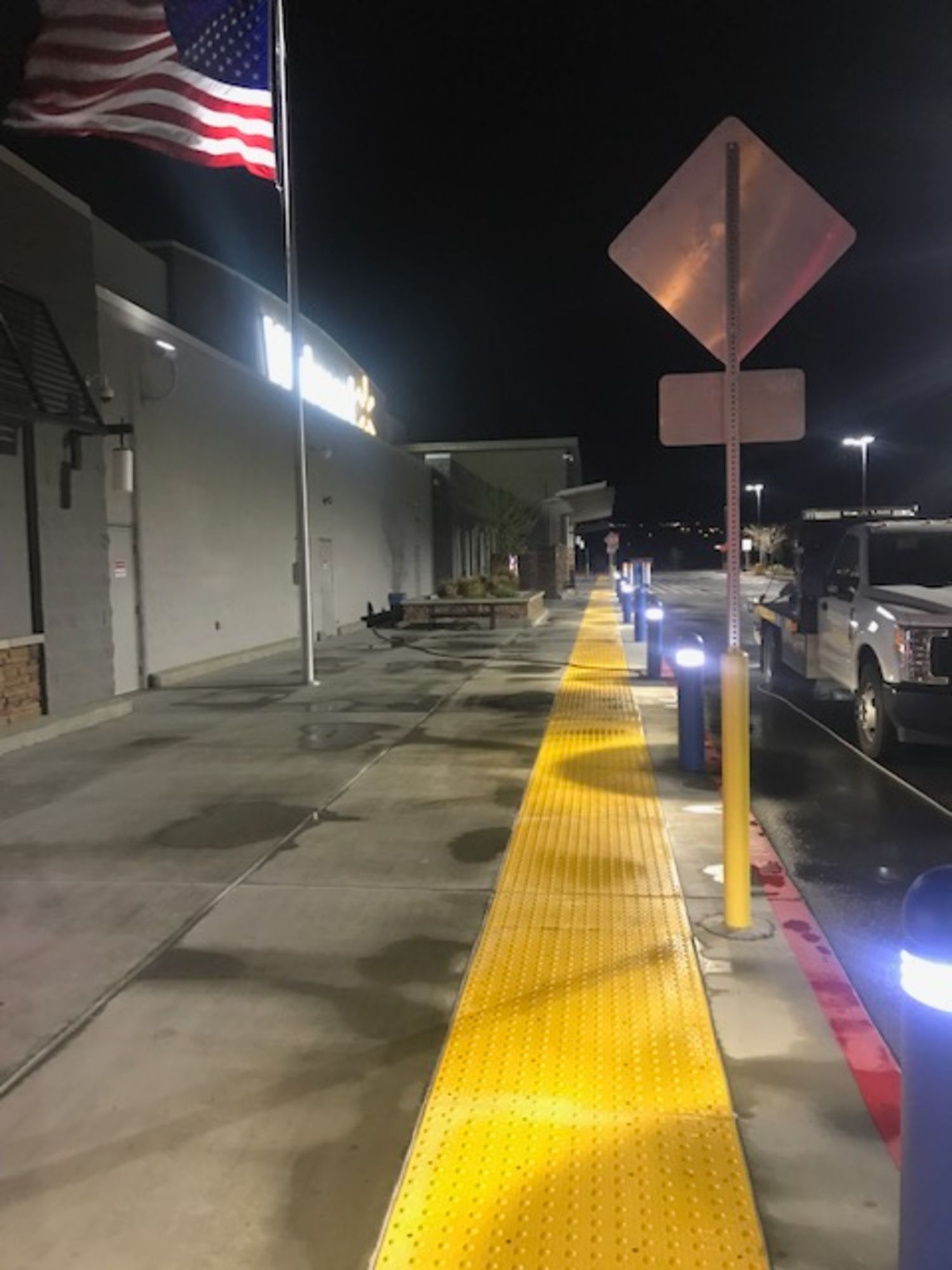 A row of cars are parked in front of a walmart store at night