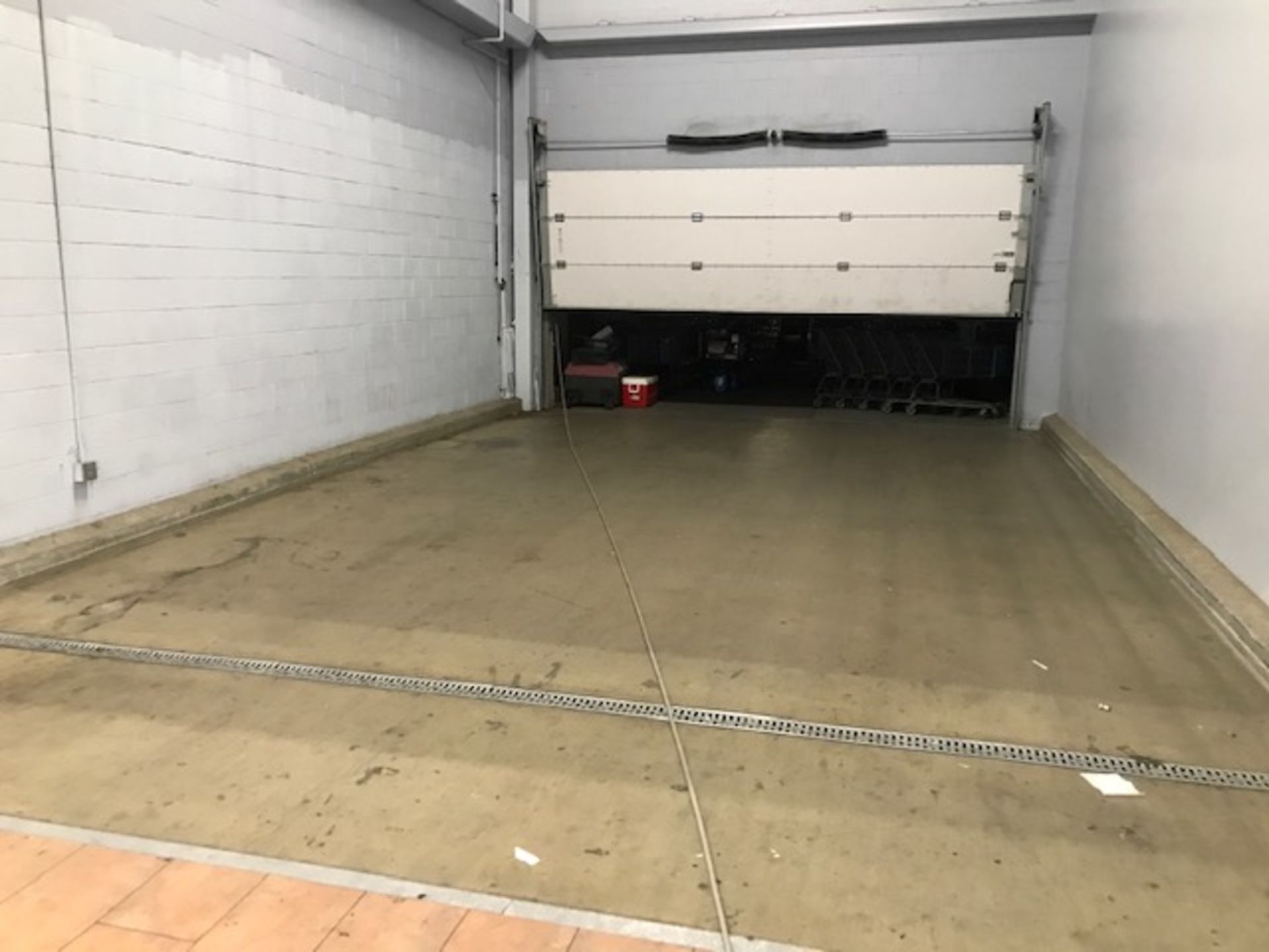 An empty garage with a white garage door open
