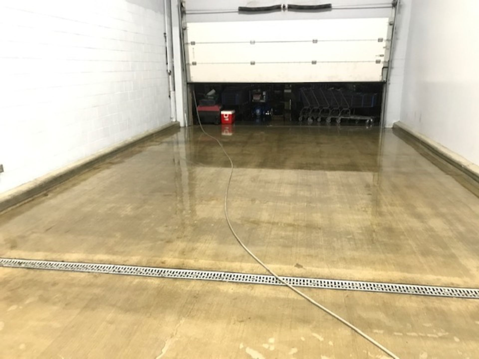 A garage with a white garage door and a drain on the floor