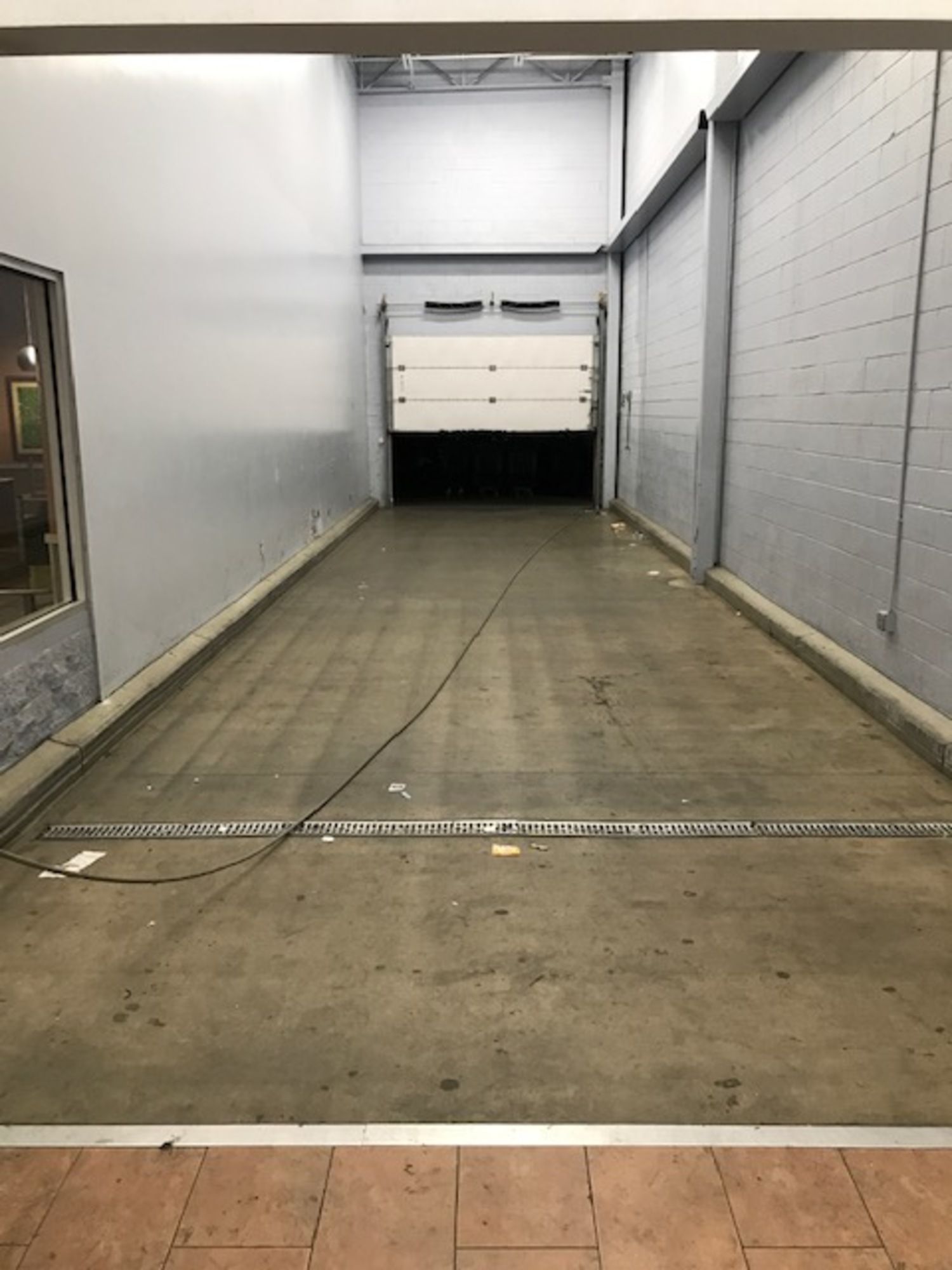 An empty warehouse with a garage door and a concrete floor.